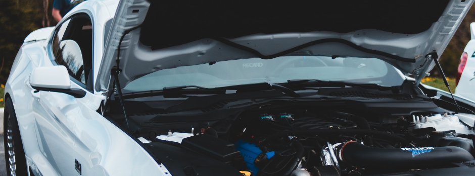 White car with open hood displaying engine for inspection